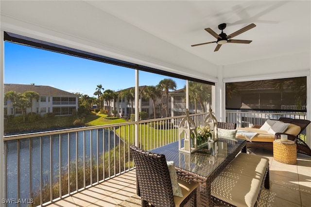 sunroom with a wealth of natural light, a water view, ceiling fan, and a residential view