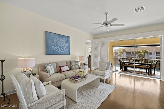 living room with a ceiling fan, visible vents, and wood finished floors