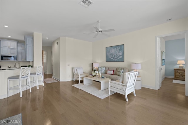 living area with baseboards, wood finished floors, visible vents, and recessed lighting