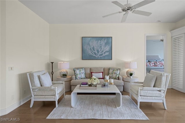 living room featuring a ceiling fan, baseboards, and wood finished floors