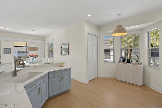 kitchen with a wealth of natural light, a sink, light wood-style flooring, and gray cabinetry