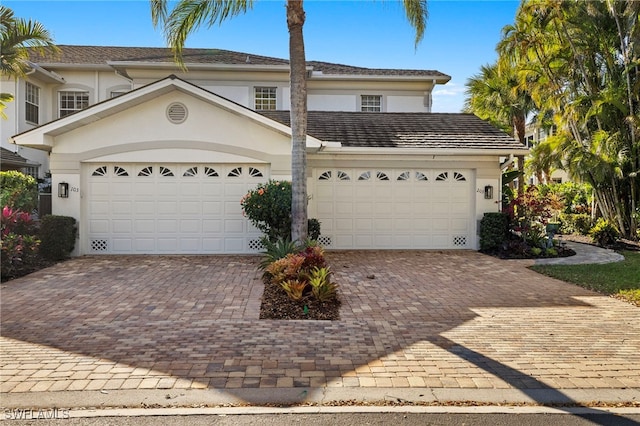 view of front of home featuring driveway, an attached garage, and stucco siding