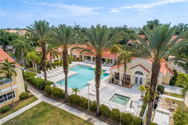 pool with fence, a community hot tub, a patio, and french doors