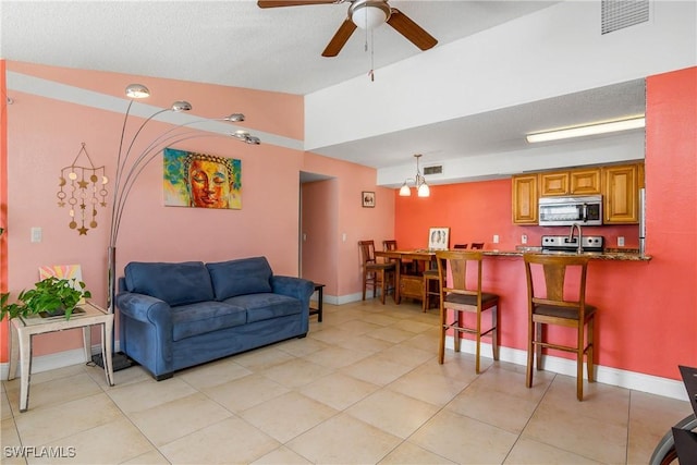 living area with a ceiling fan, visible vents, vaulted ceiling, and baseboards