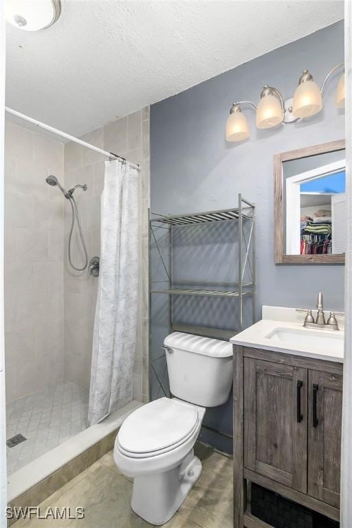 full bath with toilet, a shower stall, a textured ceiling, and vanity