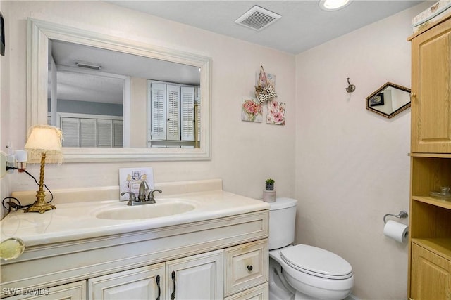 bathroom with toilet, vanity, and visible vents