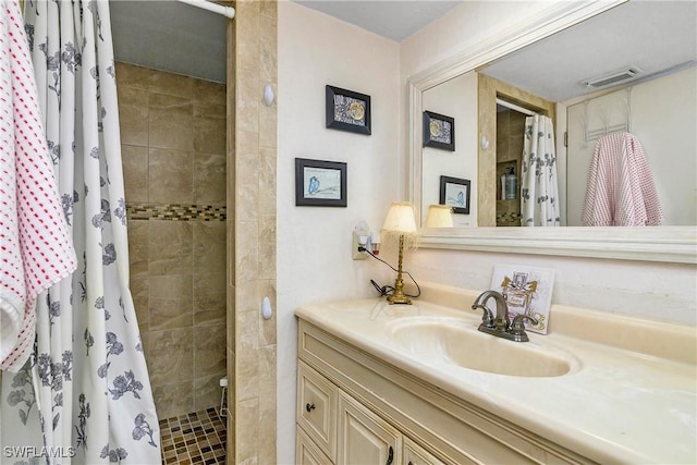 full bathroom featuring tiled shower, vanity, and visible vents