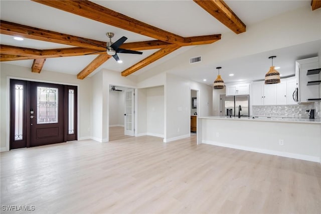 interior space featuring vaulted ceiling with beams, ceiling fan, visible vents, and baseboards