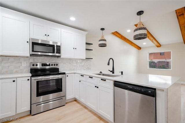 kitchen featuring beam ceiling, decorative backsplash, appliances with stainless steel finishes, a sink, and a peninsula