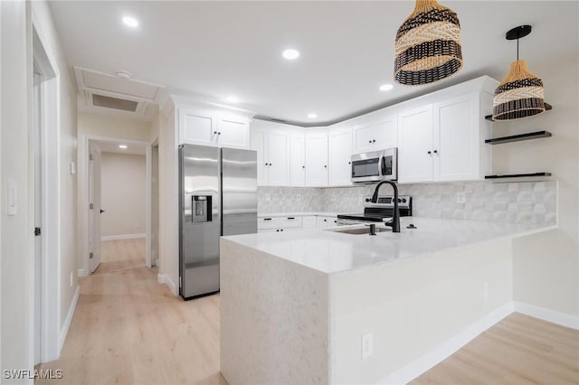 kitchen featuring a peninsula, light wood-style flooring, appliances with stainless steel finishes, and white cabinets