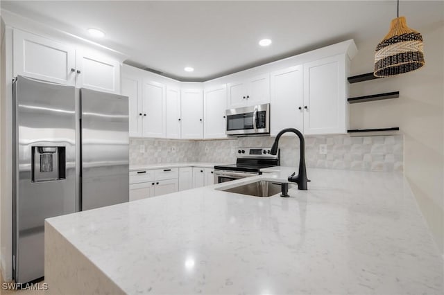 kitchen with stainless steel appliances, a sink, decorative backsplash, and light stone countertops