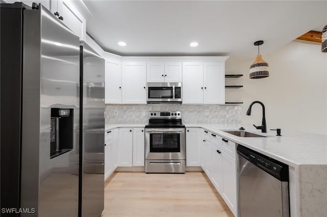 kitchen with a peninsula, tasteful backsplash, stainless steel appliances, and a sink