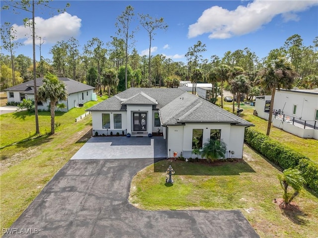 view of front of home featuring stucco siding, driveway, a front yard, and roof with shingles