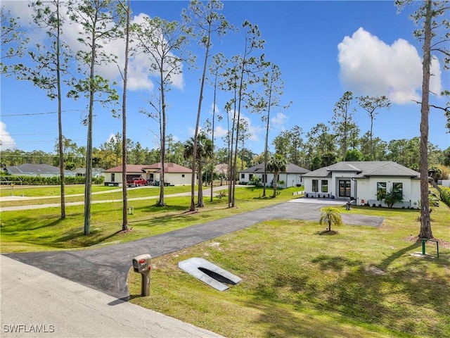 exterior space featuring aphalt driveway and a yard