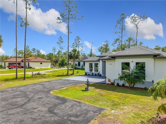 view of front of property featuring aphalt driveway, roof with shingles, a front yard, and stucco siding