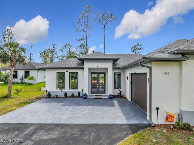 exterior space with driveway, an attached garage, stucco siding, french doors, and a lawn