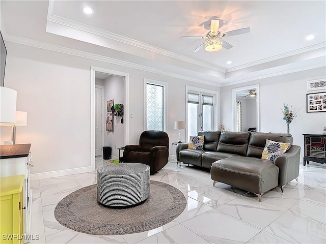 living room featuring a raised ceiling, marble finish floor, ornamental molding, baseboards, and ceiling fan