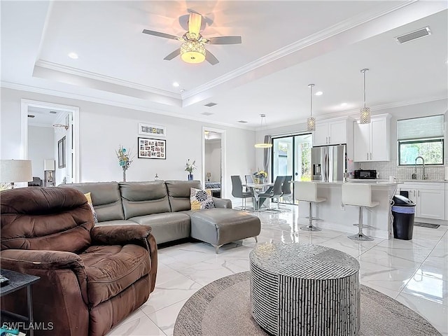 living area with a raised ceiling, plenty of natural light, and marble finish floor