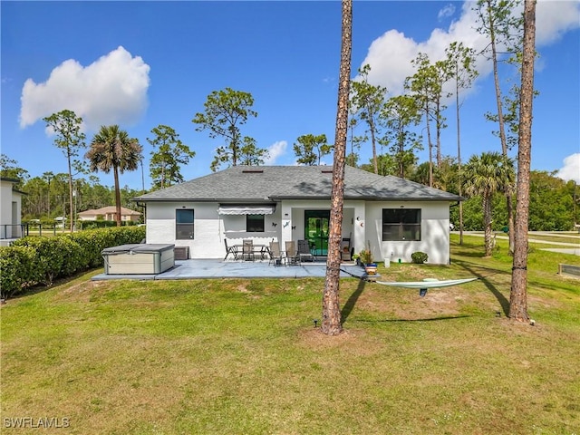 back of property featuring a patio area, a lawn, a hot tub, and stucco siding