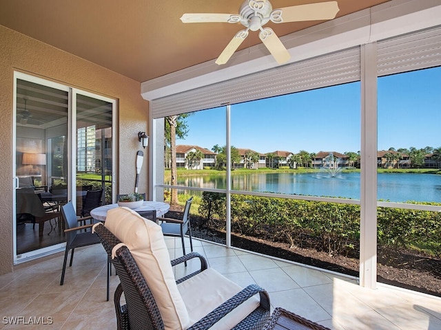 sunroom / solarium with a ceiling fan, a water view, and a residential view