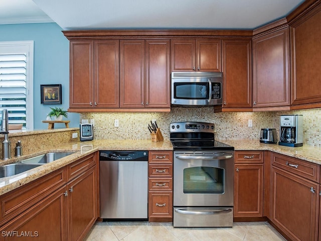 kitchen with light stone counters, a sink, appliances with stainless steel finishes, crown molding, and tasteful backsplash