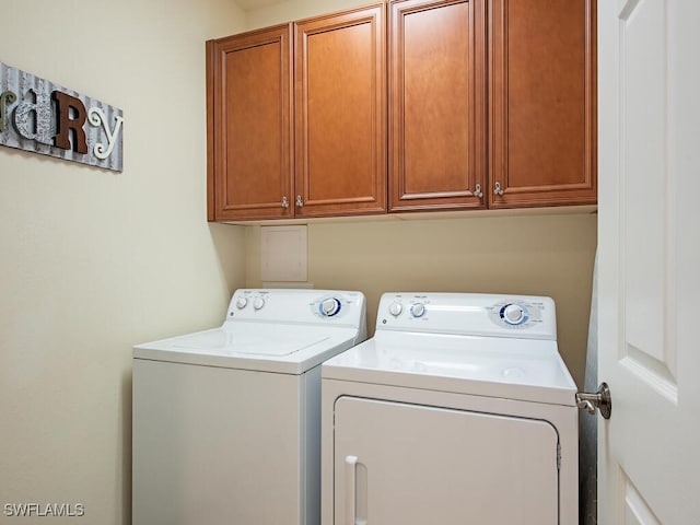 clothes washing area featuring washing machine and clothes dryer and cabinet space