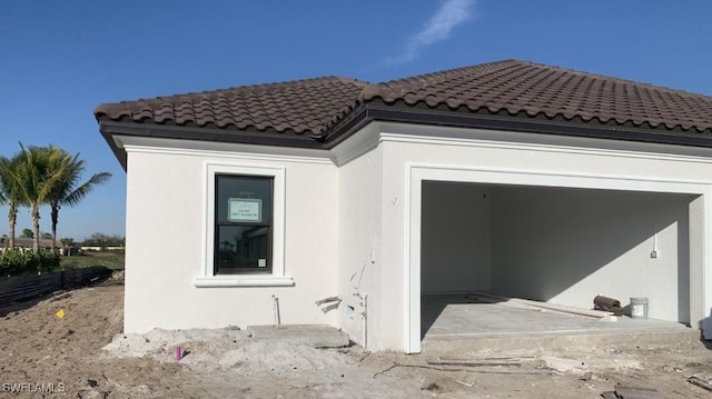 exterior space with a tiled roof, an attached garage, and stucco siding