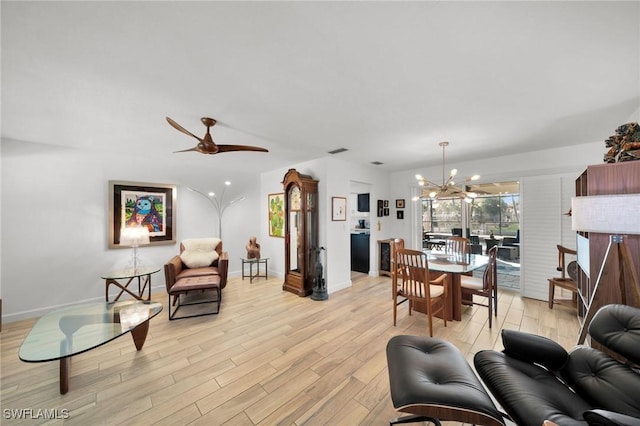 living area featuring ceiling fan with notable chandelier, light wood-type flooring, visible vents, and baseboards