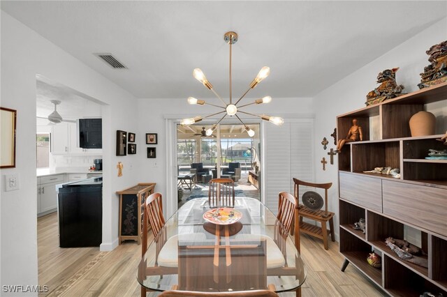 dining space with light wood finished floors, visible vents, and a notable chandelier