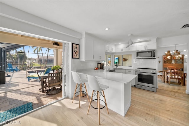 kitchen featuring light countertops, appliances with stainless steel finishes, a ceiling fan, white cabinets, and a sink