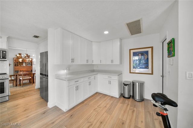 kitchen featuring appliances with stainless steel finishes, light countertops, light wood-type flooring, and visible vents