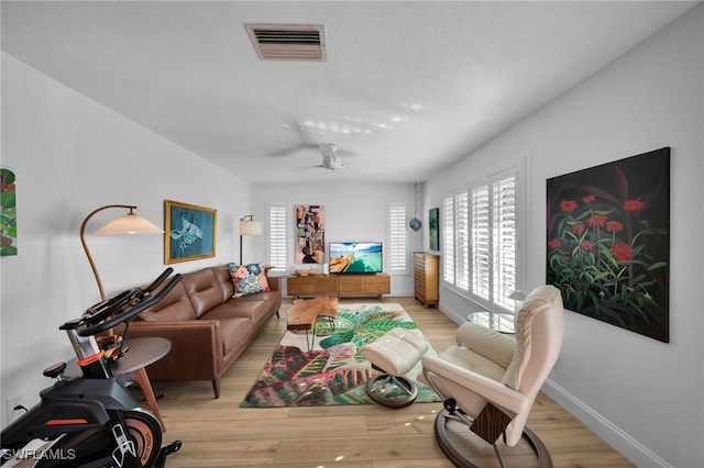 living room with baseboards, visible vents, ceiling fan, a textured ceiling, and light wood-type flooring