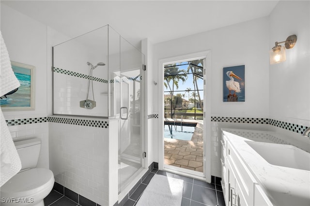 bathroom featuring toilet, a shower stall, tile walls, and tile patterned floors