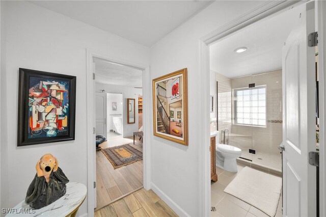 hall with light wood-style flooring and baseboards