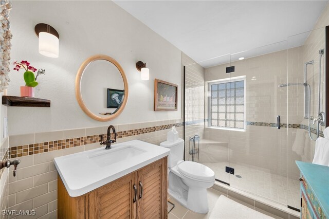 full bathroom featuring a stall shower, vanity, and tile walls