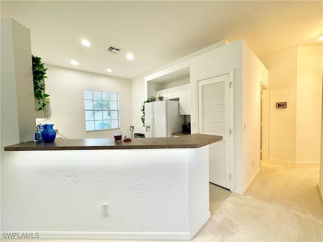 kitchen with light carpet, a peninsula, visible vents, white fridge with ice dispenser, and dark countertops