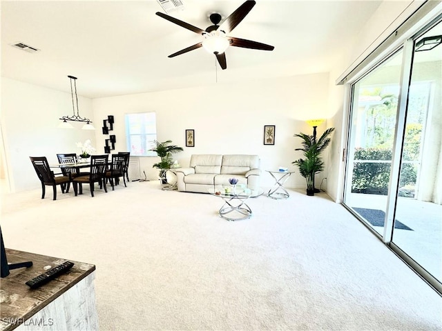 carpeted living room with ceiling fan and visible vents