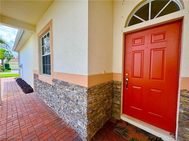 doorway to property with stone siding and stucco siding