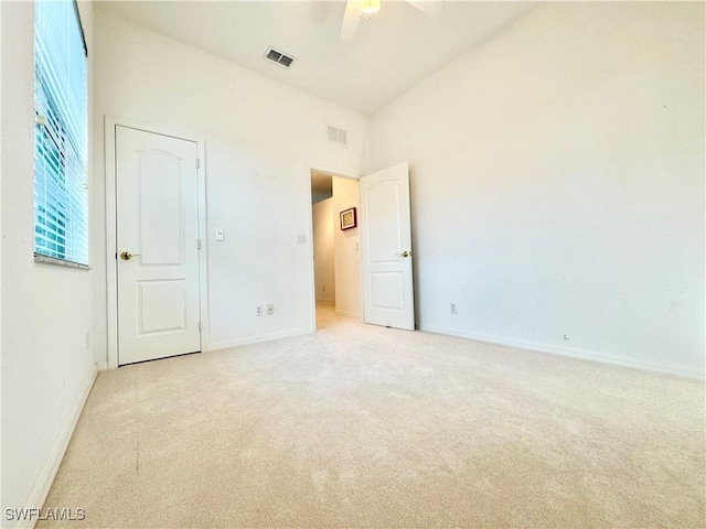 unfurnished bedroom featuring light carpet, a towering ceiling, visible vents, and baseboards