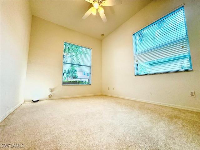 carpeted empty room featuring lofted ceiling, baseboards, and a ceiling fan