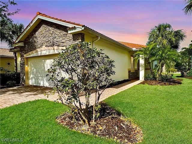 view of home's exterior featuring a garage, a tile roof, a lawn, and stucco siding