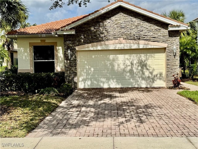 view of front of home with a garage, a tiled roof, decorative driveway, and stucco siding