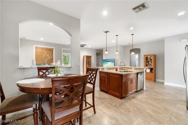 kitchen with brown cabinets, recessed lighting, visible vents, a sink, and dishwasher