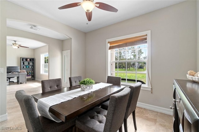 dining space featuring arched walkways, ceiling fan, and baseboards