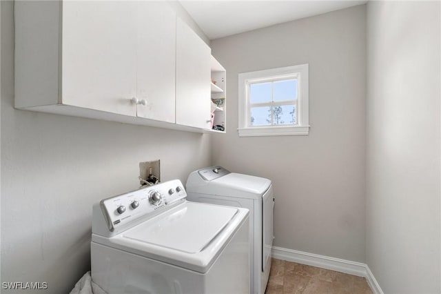 clothes washing area featuring cabinet space, washing machine and dryer, and baseboards