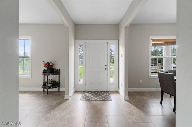 foyer entrance with plenty of natural light, baseboards, and tile patterned flooring