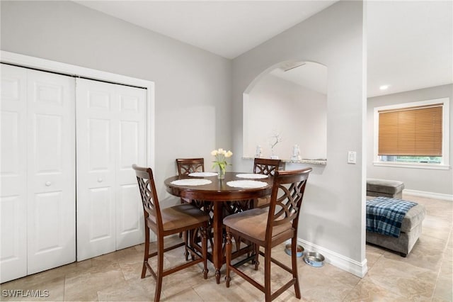 dining space with arched walkways and baseboards