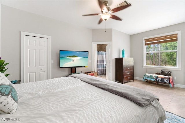 tiled bedroom featuring a closet, a ceiling fan, and baseboards