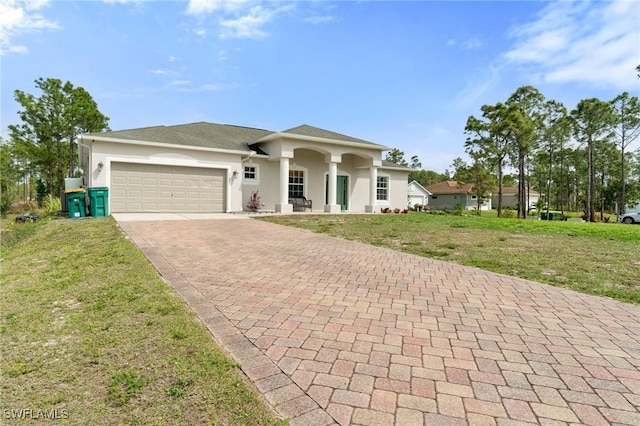 view of front facade with a garage, decorative driveway, a front lawn, and stucco siding