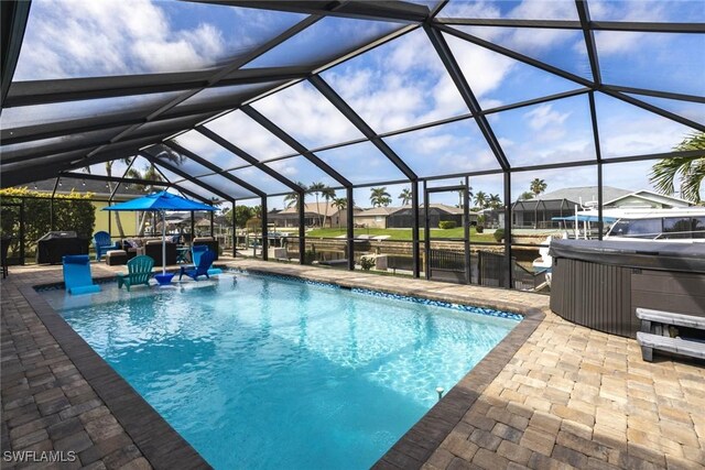 outdoor pool with a patio area, a lanai, a residential view, and a hot tub